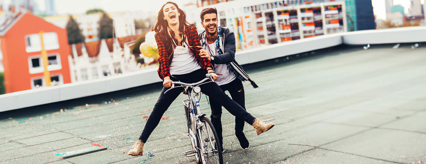 Junger Mann schiebt lachende Frau auf Fahrrad an