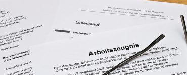 Arbeitszeugnis liegt auf Tisch mit Brille darauf