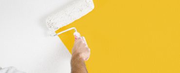 Maler streicht gelbe Wand weiß