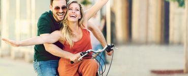 Junges gklückliches Paar auf einem Fahrrad