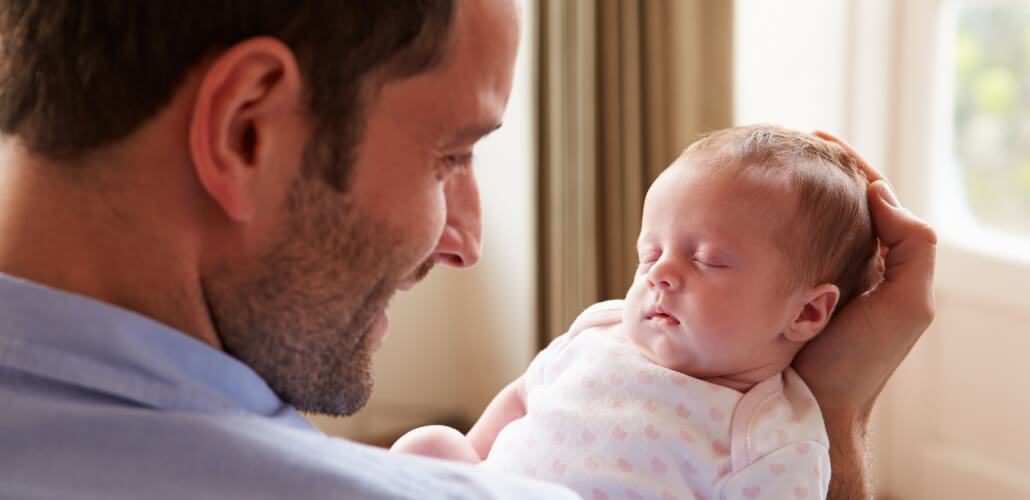 Junger Vater mit Säugling im Arm