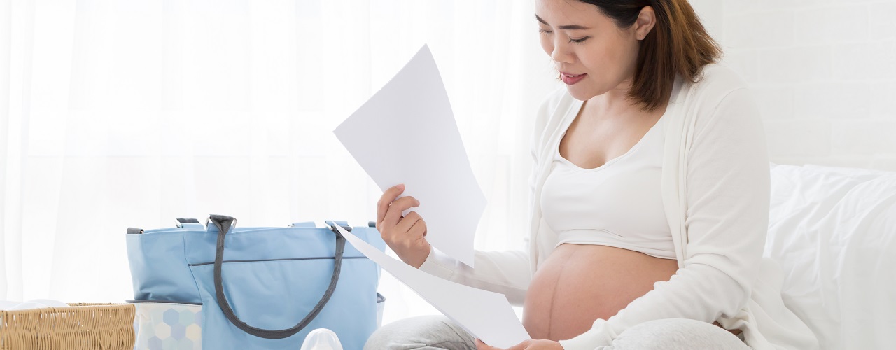 Eine schwangere Frau plant mit einer Checkliste ihre Schwangerschaft