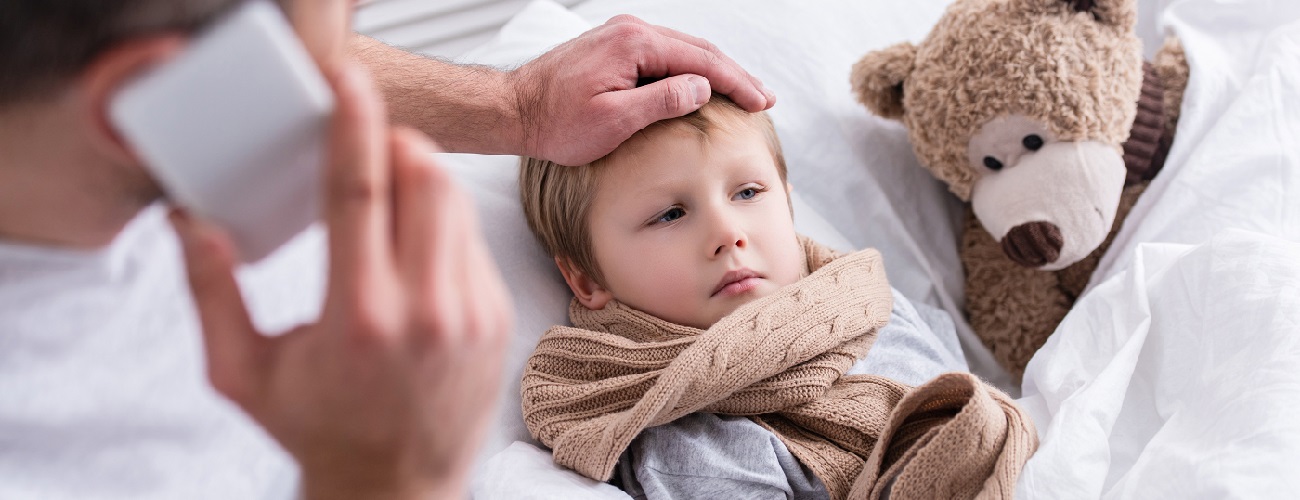 Vater kümmert sich um seinen kranken Sohn im Bett