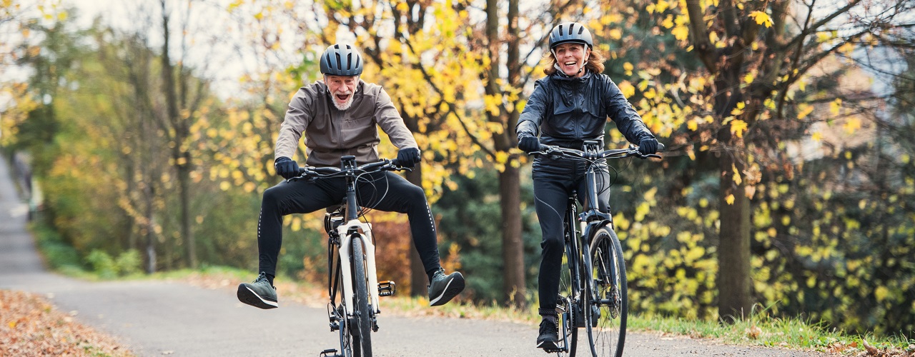 Zwei Personen fahren mit einem E-Bike oder Pedelec einen Waldweg entlang