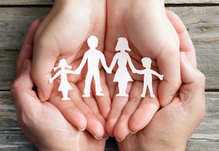 Hände, die eine symbolische Familie in den Händen hält