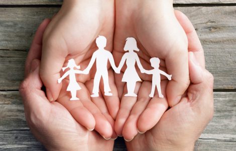 Hände, die eine symbolische Familie in den Händen hält