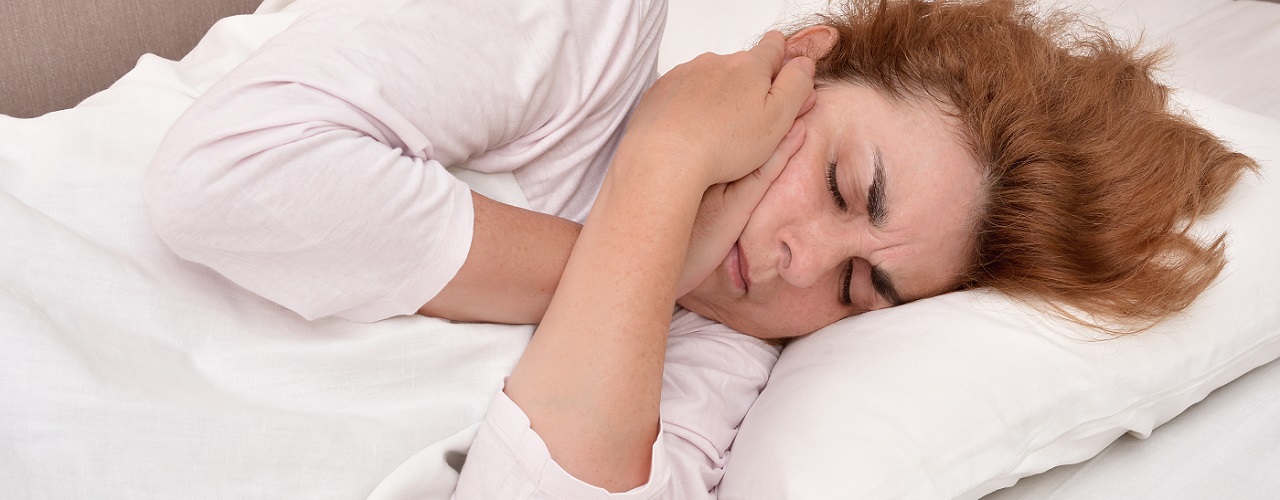 Frau liegt mit Schmerzen im Bett