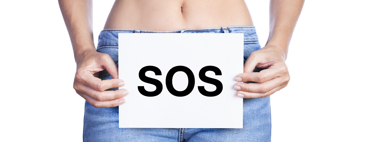 Frau in Jeans hält sich ein SOS-Schild vor die Blase
