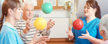 Eine Gruppe von Senioren und Betreuern in einem Pflegeheim spielen Ball