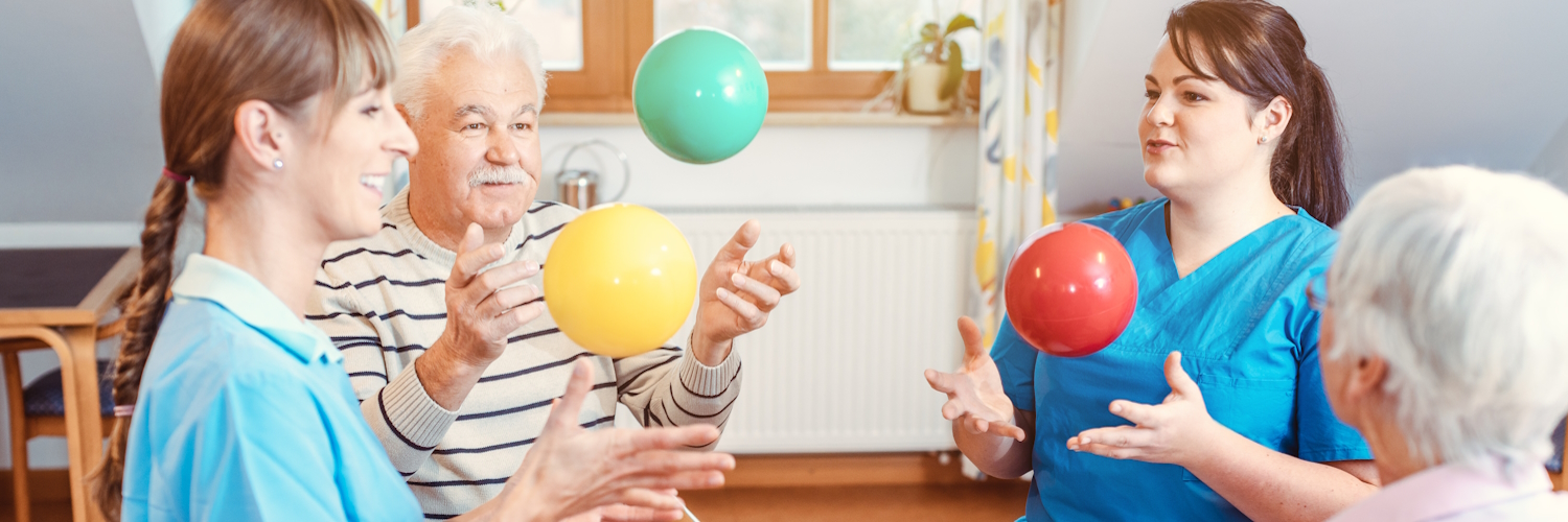 Eine Gruppe von Senioren und Betreuern in einem Pflegeheim spielen Ball