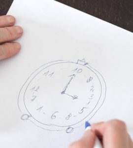 Eine Nahaufnahme von einem DIN A4 Blatt, auf dem Eine Uhr gezeichnet wurde