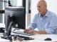 Mann sitzt im Buero am Computer