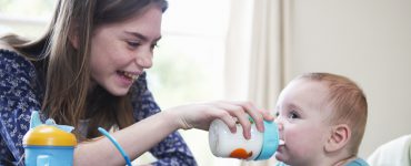 Mädchen füttert Baby mit Trinkflasche