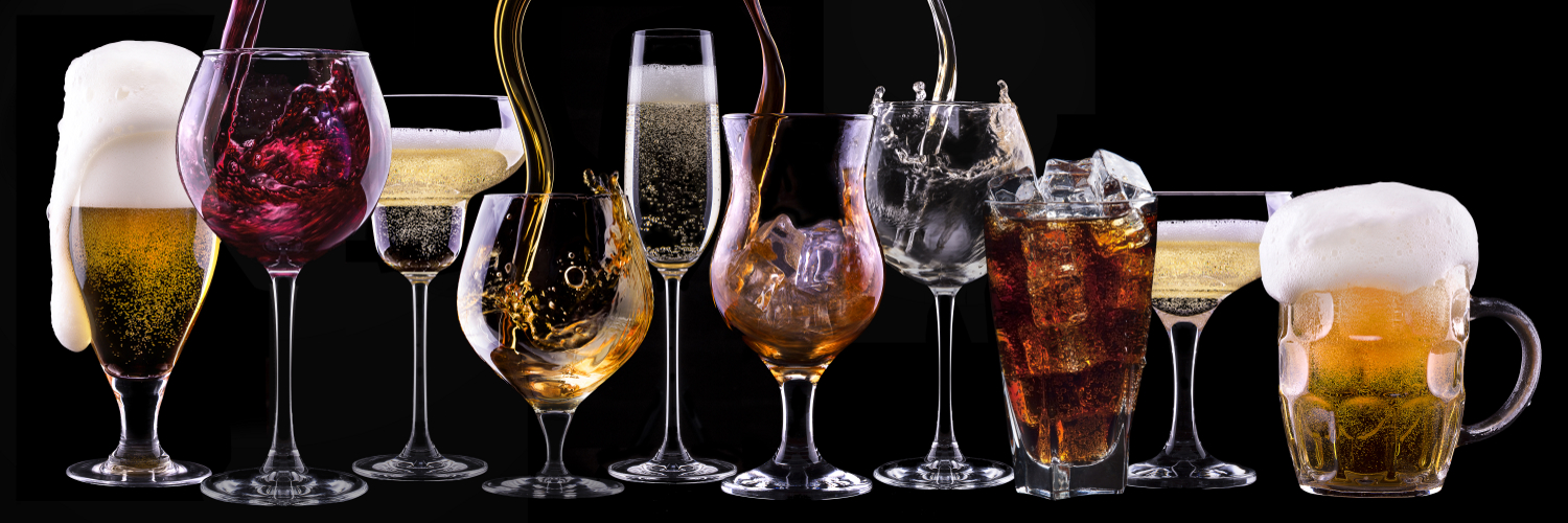 Unterschiedliche alkoholische Getränke in Gläsern vor einem schwarzen Hintergrund.