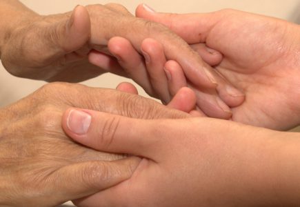 Eine junge Frau hält die Hände einer Seniorin