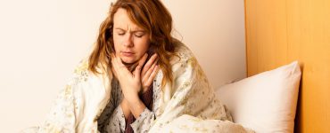 Frau mit Halsschmerzen im Bett