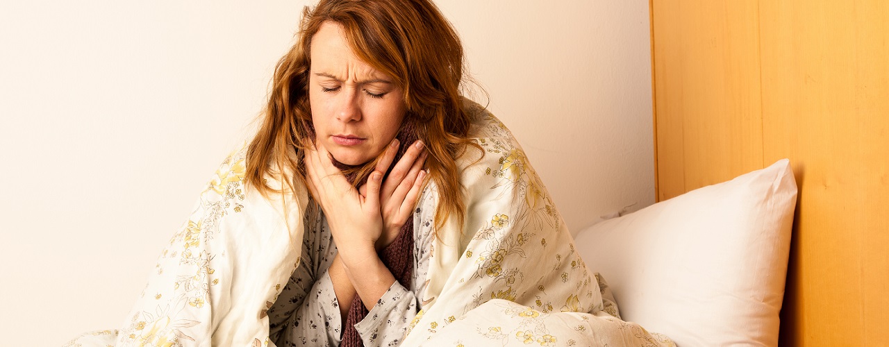 Frau mit Halsschmerzen im Bett