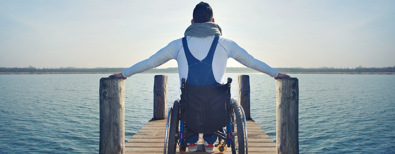 Mann in Rollstuhl auf Steg am See