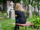 Frau sitzt auf Bank auf Friedhof