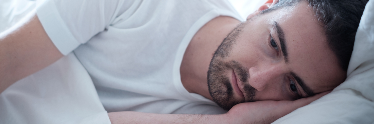 Mann liegt depressiv im Bett