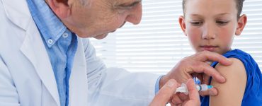 Ein Arzt führt bei einem kleinen Jungen eine Impfung durch