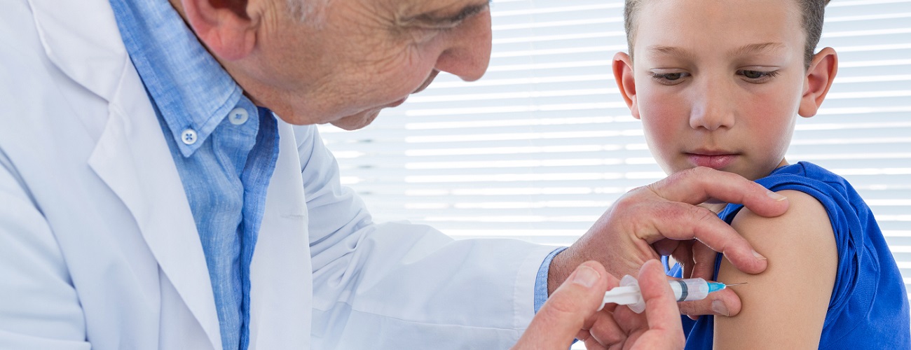 Ein Arzt führt bei einem kleinen Jungen eine Impfung durch