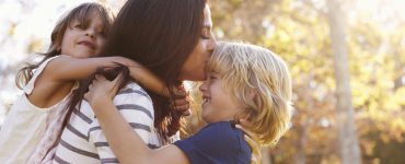 Eine Mutter mit zwei Kindern vor einem Wald.