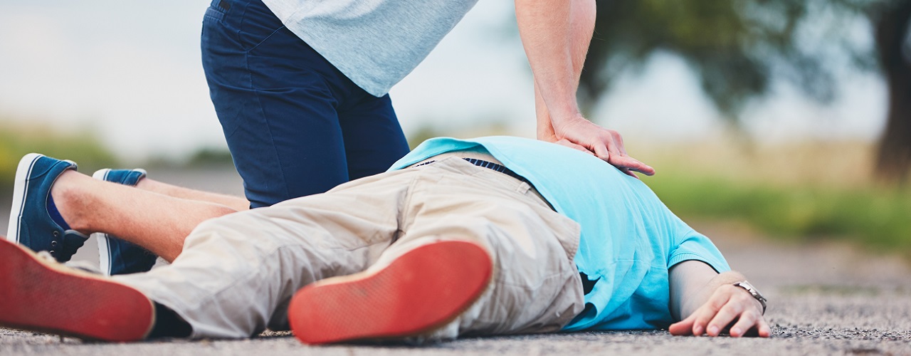 Ersthelfer versorgt einen am Boden liegenden Patienten mit Herzinfarkt