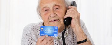 Seniorin am Telefon Kreditkrarte in der Hand