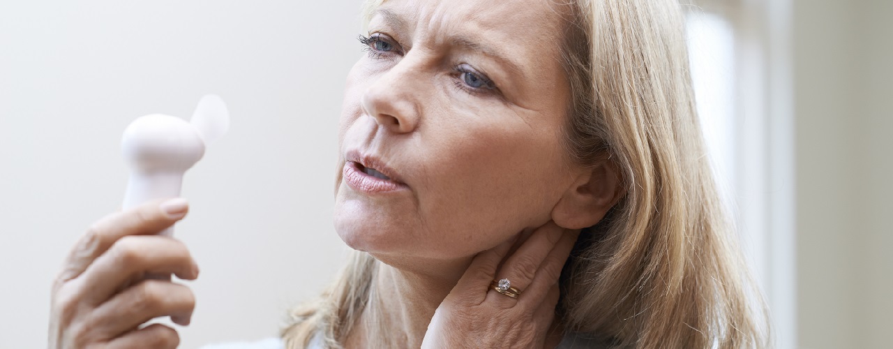 Ältere Frau mit Ventilator kühlt ihr Gesicht