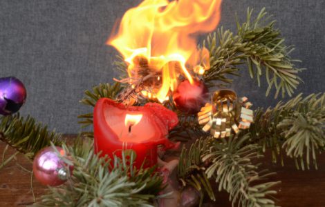 Das Feuer einer Kerze geht auf einen Tannenzweig über
