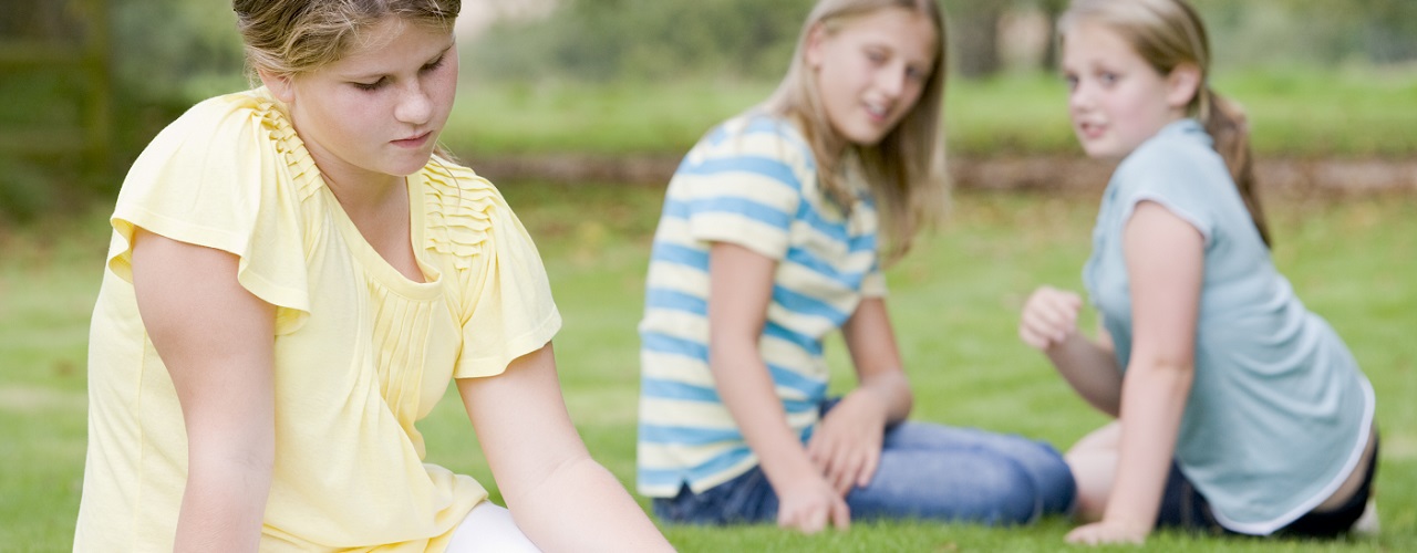 Mädchen sitzt abseits zweier Kinder